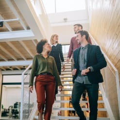 Group of young professionals walk down a staircase in a modern office.