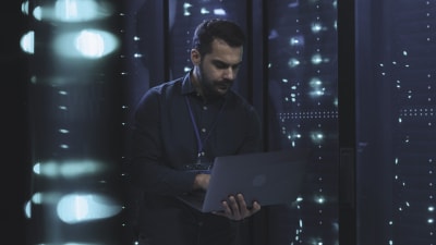 Person in datacenter holding a laptop.