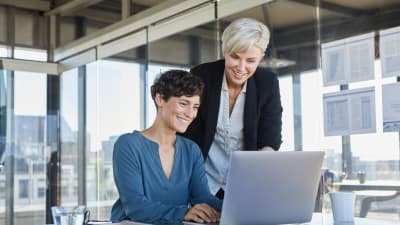Two women looking at laptop together in office