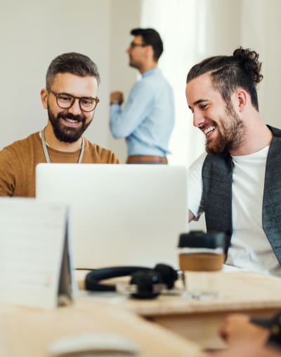 Four young professionals collaborate in front of computers.