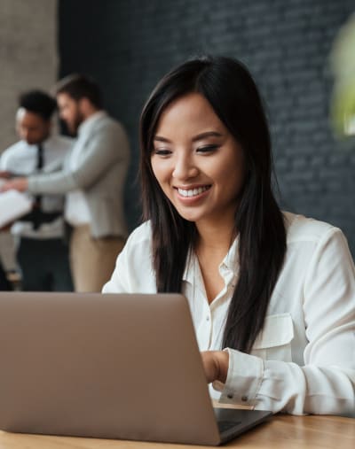 A marketing professional smiles while working on a laptop computer, confident the asset they’ve activated is in-brand.