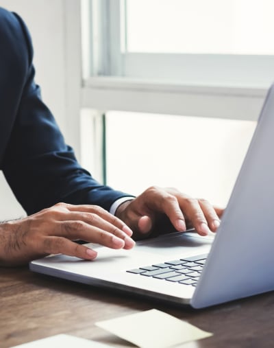 Hands type on an open laptop.