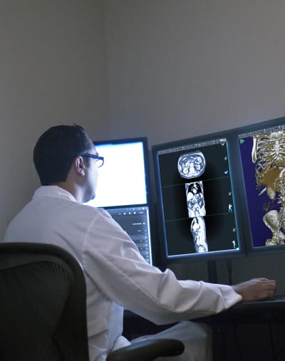 A radiologist  sits at a computer and interprets medical images. 