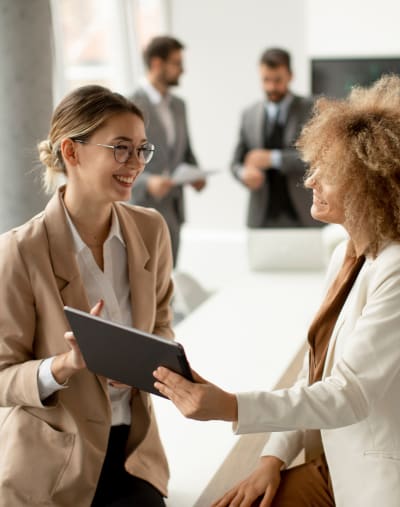 Two people stand, smile and look at a tablet.