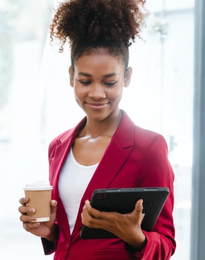 Person smiles and holds a tablet and a cup of coffee.