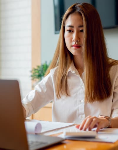 Person sits and looks at a tablet. There is paperwork on the table.