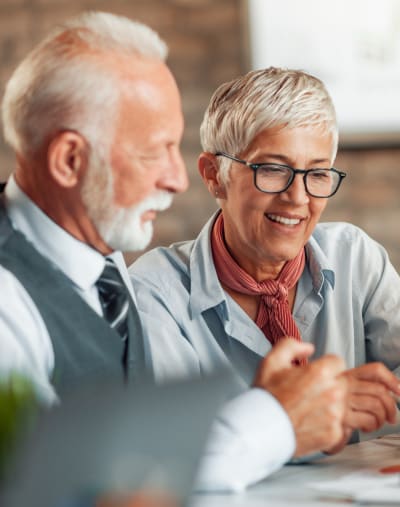 Two people interact and look over paperwork. One has a beard and the other has glasses.