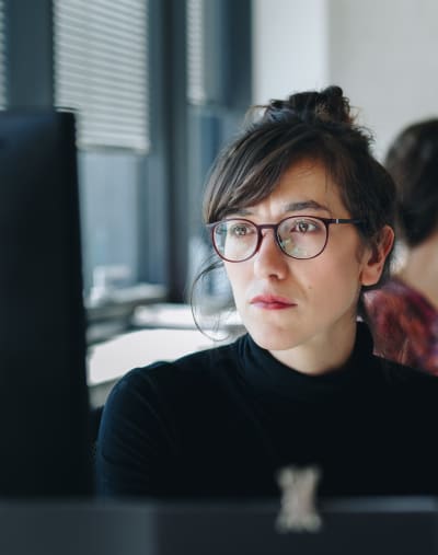 Person with glasses stares at a computer monitor.