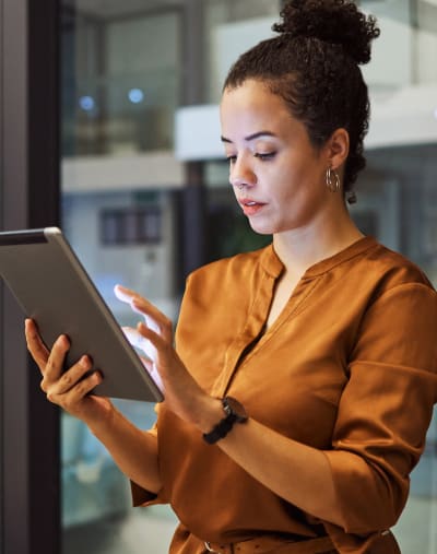 Person stands and works in an office while holding a tablet. 