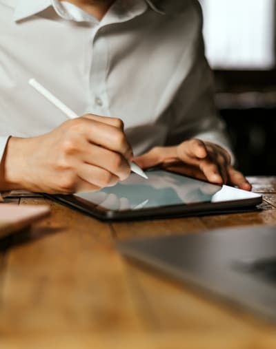 A person uses a stylus to sign a lending document on a tablet. 