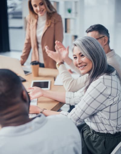 Four people smile and interact in an office setting.