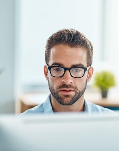 Person in glasses sitting at a desktop computer.