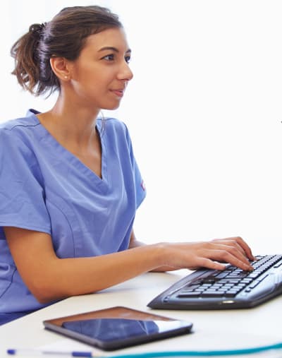 Person sits at a desktop computer with their hands on the keyboard.