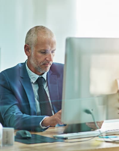 Healthcare professional wearing a suit works at a desktop computer in an office.