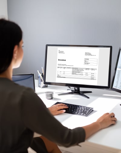 Healthcare professional reviews a document on a desktop computer. 
