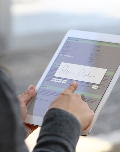 Person holds a digital tablet with a signature block.