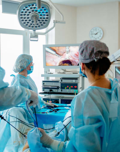 Clinicians wearing scrubs look at a monitor in a clinical setting.