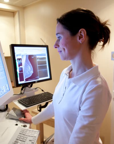 A technologist examines breast imaging on digital monitors. 