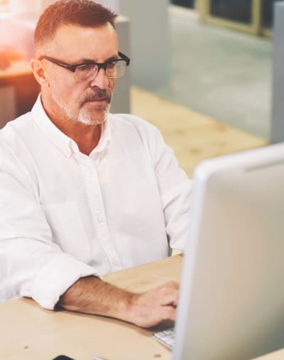 Person in business clothing looks at a desktop computer monitor. 