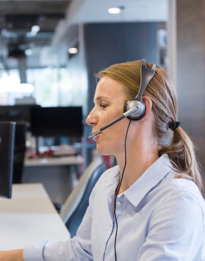 A person with a headset sits and talks in an office.
