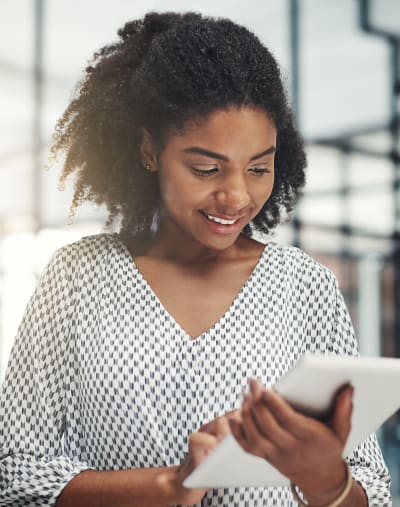 Person stands, smiles and looks at a tablet.