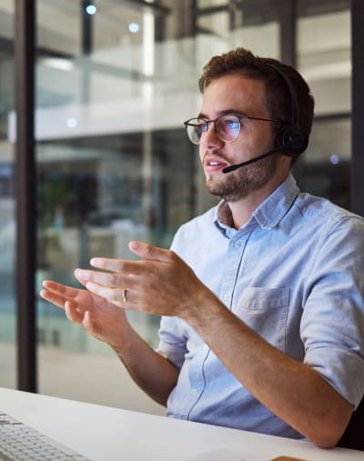 A managed services expert sits at a desk with a headset and collaborates virtually with a customer.