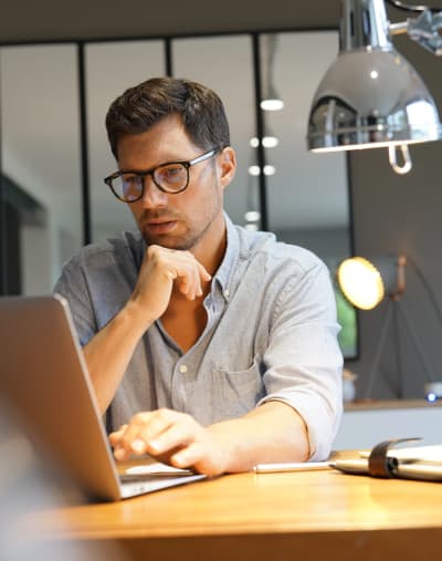 Office worker at desk looking at laptop