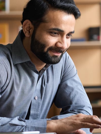 Person sits in office setting at laptop.