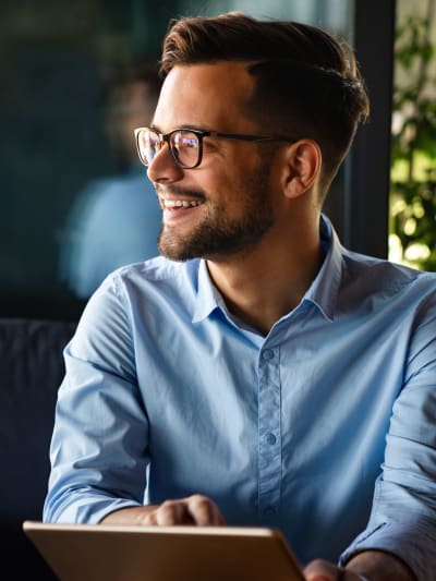 A remote worker smiles and uses a tablet.