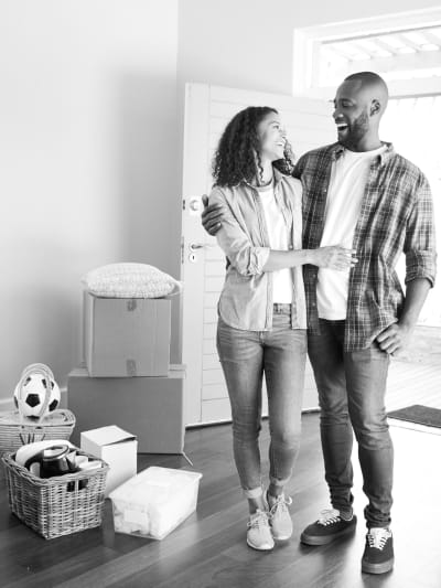 Black-and-white photo of a couple in a barren house with cardboard boxes around them.