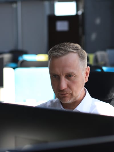 Person in white button-down shirt sits at a computer.