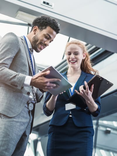 Business people look at tablet computers in a modern steel and glass office.