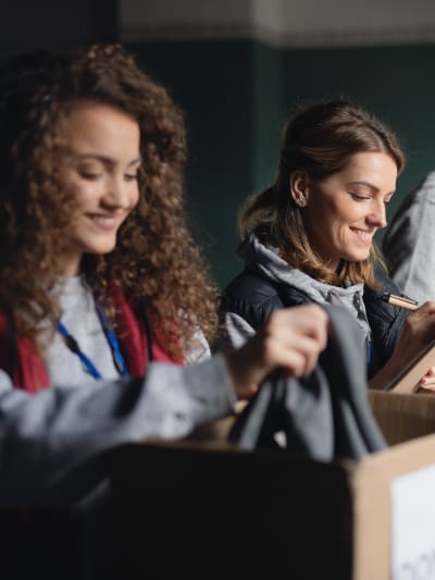 A group of employees volunteering at a donation center collect and track incoming goods.