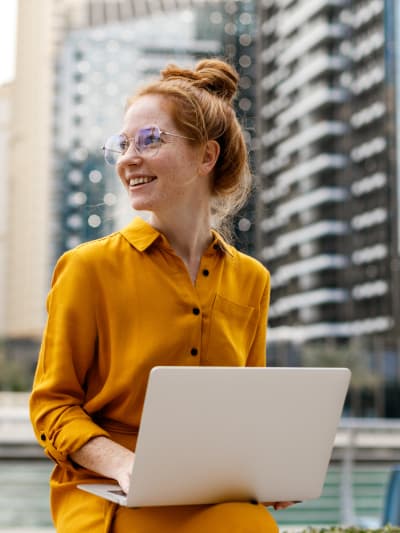 Young woman sitting outside and working on laptop