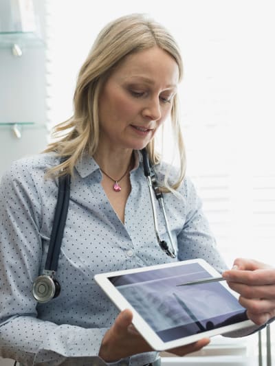 Clinician holding a digital tablet pointing to a medical image.