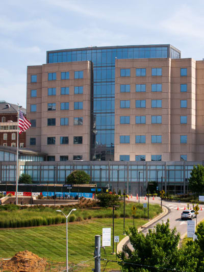 Exterior shot of a multistory glass and brick building with an American flag in front. 