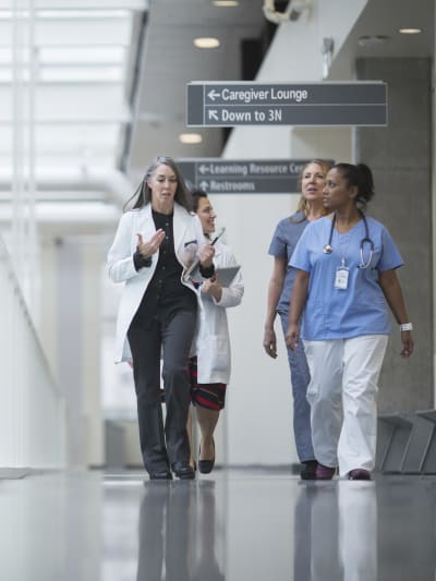 Healthcare professionals walk down a hospital hallway engaging in discussion.