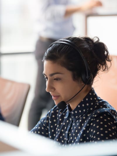 Businessperson sitting at a desk wearing a headset with microphone