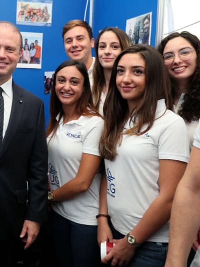 Group of people, some in T-shirts and others in suits, stand together and smile for the camera.