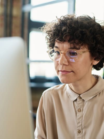 Person in casual business attire looks at a desktop computer monitor.  