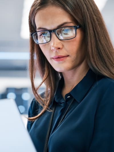 Person in glasses works on a laptop in a modern office.