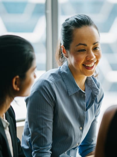 Three young professionals talk together in front of a frosted glass window.