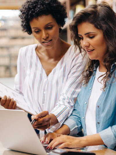 Two people in business-casual attire work together at a laptop.