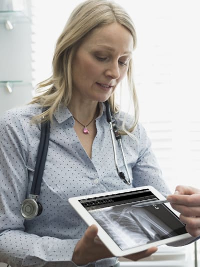 A healthcare professional shows a medical image on a tablet.