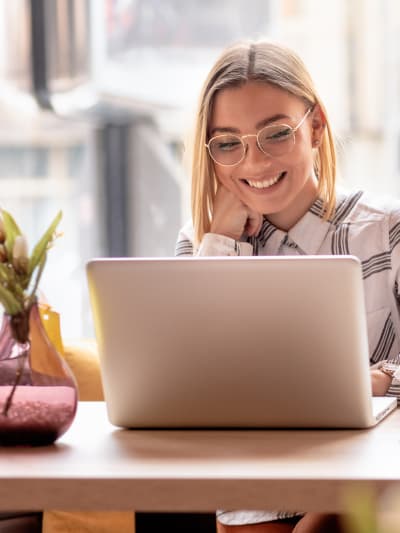 A woman smiling while looking at her laptop