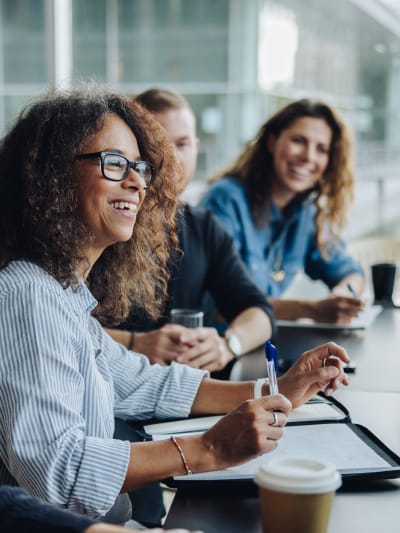 Three coworkers sit in a boardroom and consider content services platforms.