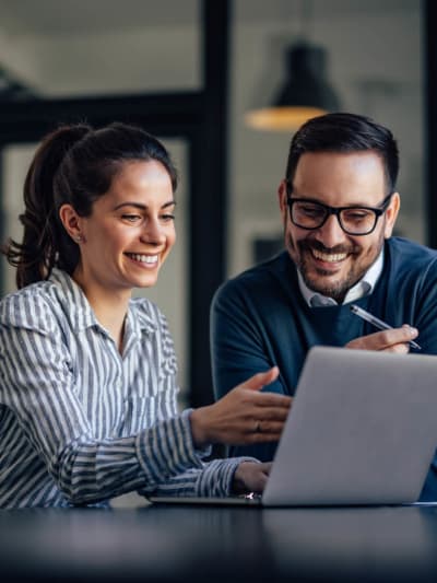 Two coworkers in office setting discussing BPA strategy on work laptop