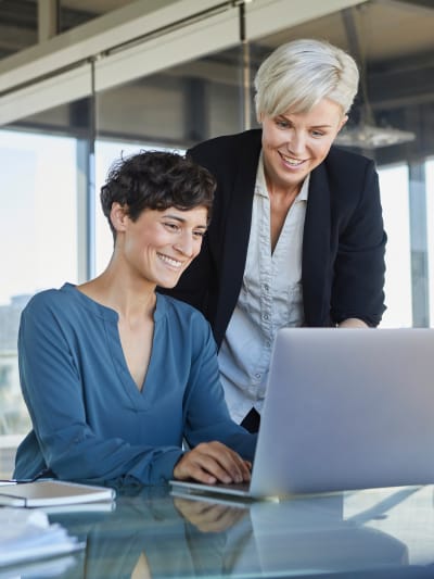 Two women looking at laptop together in office
