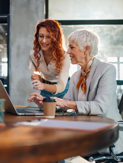 Two generation workers collaborating on a project on a laptop