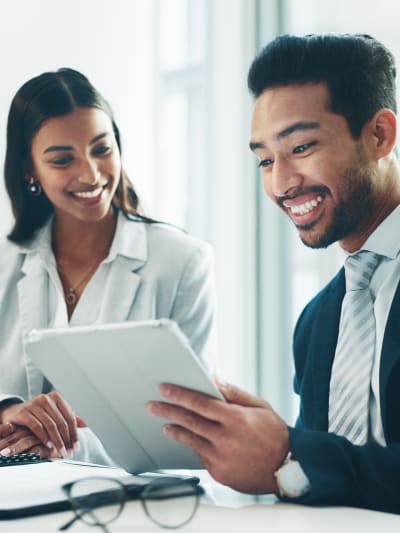 People smiling at tablet in meeting room